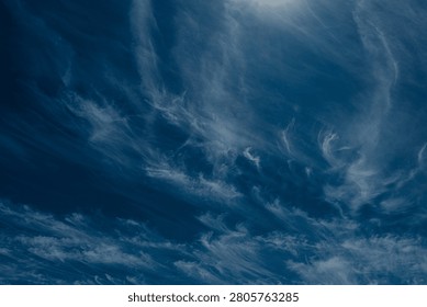 An abstract view of thin, faint clouds drifting across a deep blue sky, with ample text space and a calm, atmospheric mood.