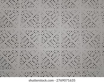 Abstract view of white perforated ceiling panels with geometric triangular pattern and small circular holes, commonly used for acoustic insulation in modern buildings and interior architecture.