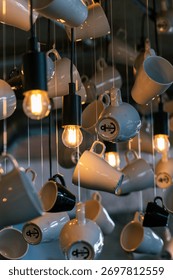 Abstract visual art installation featuring multiple ceramic coffee mugs and glowing light bulbs creating a striking ceiling pattern.