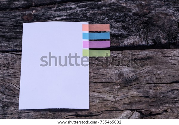 Abstract white paper with colors note tab.\
Notebook with colors note tab on wooden table background, paper\
note copy space for add text. Case study\
concept