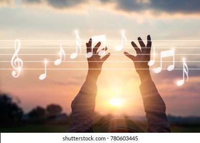Abstract woman hands touching music notes on nature background, music concept