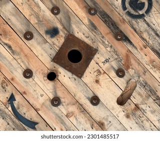 Abstract wooden background: boards with screwed-in bolts, nuts, metal sleeve, black arrow up sign. A wooden coil of a high-voltage industrial electrical cable surface.  