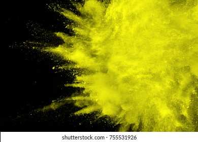 abstract yellow dust explosion on  black background.abstract yellow powder splattered on dark  background. Freeze motion of yellow powder splash.