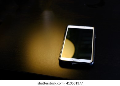 Abstract yellow light with smart phone on the table ,dark style - Shutterstock ID 413531377