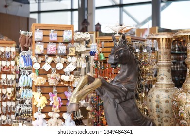 Abu Dhabai, UAE - Dec 30, 2018 : A Photo Of A Souvenir Shop At Ferrari World Theme Park With Selective Focus On The Classical Bronze Bucking Horse With Souvenir Keychains On The Background.