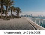 Abu Dhabi cityscape with palm trees and promenade. Landscape view of Abu Dhabi with skyscrapers on the background.