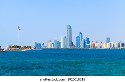 Abu Dhabi downtown. Cityscape on a summer day, skyscrapers and national flag of United Arab Emirates on the sea coast