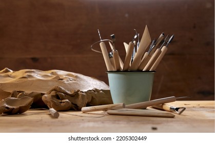 Abundance of assorted special wooden tools for sculpting pottery in metal mug placed on table with clay in professional light workshop - Powered by Shutterstock