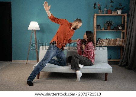 Abuse and tyranny at home concept. Aggressive nervous angry husband threatens to wife in living room interior. Relationship problems, quarrel, beating and violence. Copy space