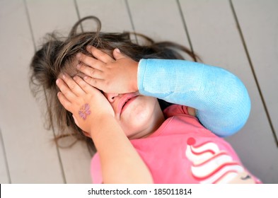 Abused Young Girl(age 3-4) With A Broken Arm Covering Here Face While Crying. Concept Photo Of Child Abuse, Violent In The Family,domestic Violent, Social Issues.Real People. Copy Space