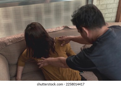 An abusive husband shoves his wife onto the couch. Example of domestic abuse and physical violence in couples. - Shutterstock ID 2258014417