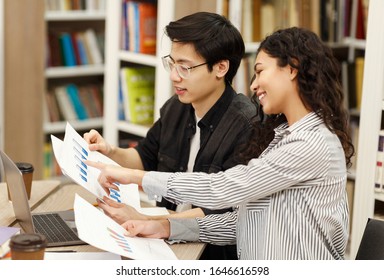 Academic Advisor. Happy Mexican Counselor Explaining Charts And Diagrams To Asian Architect Student Sitting In Library