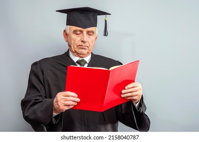 Academician, Professor, Prof Is Wearing A Cap With Tassel And Black Gown. Senior Educator Holding Red Folder. Doctor Of Philosophy, Learned Man From A University Or College.