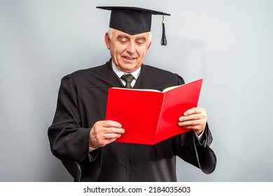 Academician, Professor, Prof Is Wearing A Cap With Tassel And Black Gown. Senior Educator Holding Red Folder. Doctor Of Philosophy, Learned Man From A University Or College Alumni Ceremony.