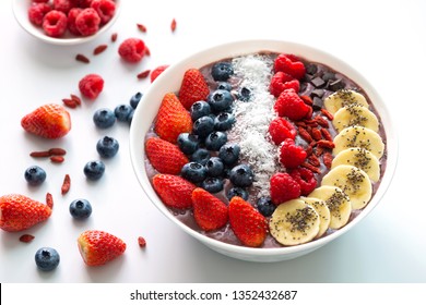 Acai Berry Superfoods Smoothies White Bowl With Chia Seeds, Strawberry, Goji Berry, Coconut, Blueberry, Raspberry Toppings, And Chocolate Chip On White Background