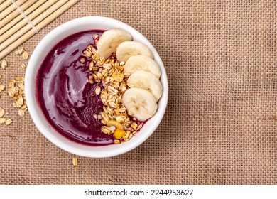 Acai bowl with banana and granola on textured jute canvas.  - Powered by Shutterstock