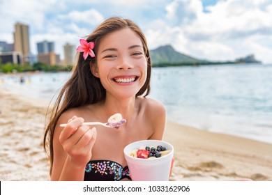 Acai Breakfast Smoothie Bowl Eating Woman Enjoying Hawaii Food On Waikiki Beach, Honolulu. Asian Girl Happy Smiling On Detox Diet Eating Healthy Local Fruit Snack.