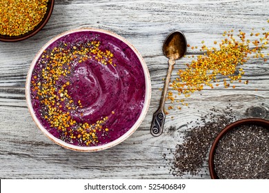 Acai breakfast superfoods smoothies bowl with chia seeds, bee pollen toppings. Immune boosting, anti inflammatory smoothie with turmeric, honey, maca powder. Overhead, top view, flat lay, copy space.