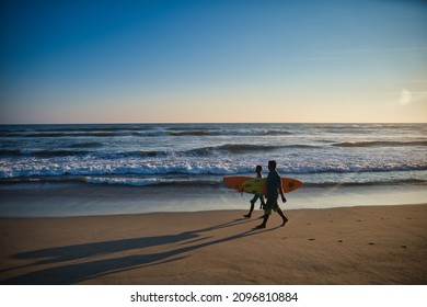 Acapulco, Mexico - December 3, 2021: Surfers walking on Acapulco beach at sunset, "Barra Vieja" beach