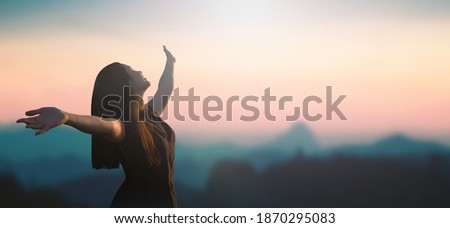 Acceptance concept: Happy girl raised hand on blurred mountain sunrise background. Phang-nga, Thailand, Asia