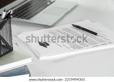 Acceptance letters from universities with pen and laptop on white table indoors, closeup