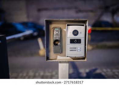 Access control panel with intercom and keypad, mounted on a post, illuminated at night, highlighting modern security features and technology in urban environment
