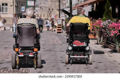 Accessible Environment For People With Disabilities. Woman And Man In Motorized Wheelchair Are Resting On City Street.