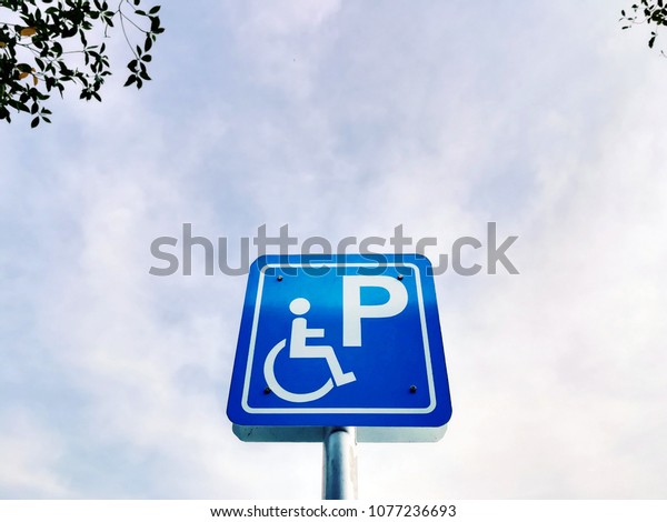 Accessible\
parking sign with sky is full of\
clouds.