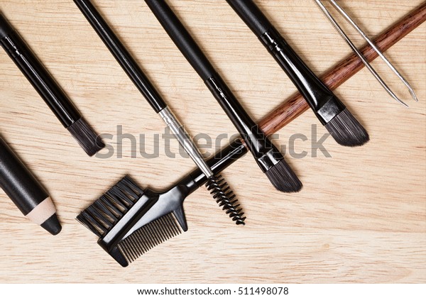 Accessories for care\
of brows and lashes: brow comb / brush combo, spoolie brush, angled\
brushes, eyebrow pencil, tweezers on wood background. Eyebrow and\
eyelashes grooming\
tools