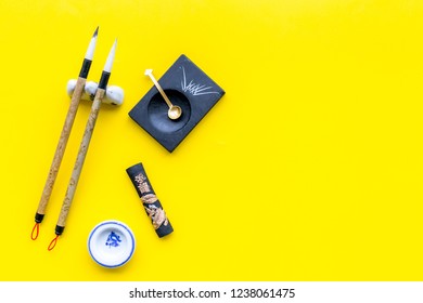 Accessories For Chinese Or Japanese Calligraphy. Special Writting Pen, Ink On Yellow Background Top View Copy Space