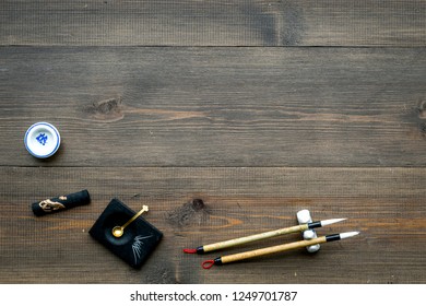 Accessories For Chinese Or Japanese Calligraphy. Special Writting Pen, Ink On Dark Wooden Background Top View Space For Text