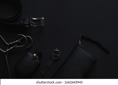 Accessories for men's beauty on a monochromatic background.
Watch, perfume, belt, hanger, wallet leather. Minimalist black trend 2020. Top view with copy space Flatlay.