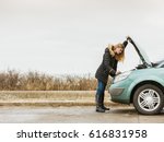 Accident and breakdowns with auto concept. Blonde woman and broken down car on road checking problem in engine