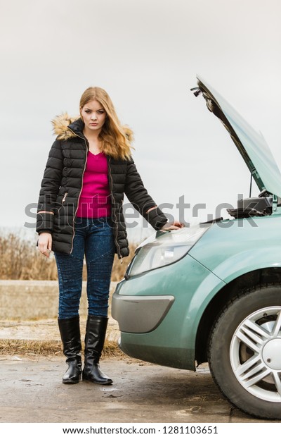 Accident and\
breakdowns with auto concept. Blonde woman and broken down car on\
road checking problem in\
engine