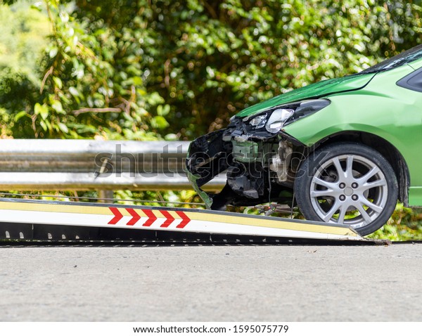 accident Car Slide on\
 truck for move. Green car have damage by accident on road take\
with slide truck move .\
I