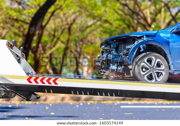 accident Car Slide on\
truck for move. Blue car have damage by accident on road take with\
slide truck move . 