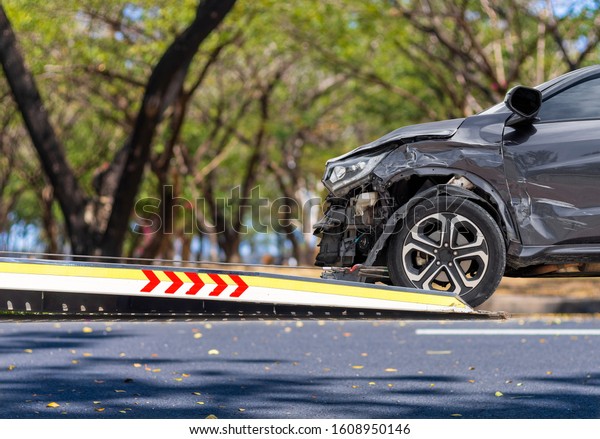 accident Car Slide on  truck for move. Balck\
car have damage by accident on road take with slide truck move .\
Isolate on white\
background.
