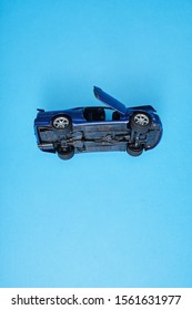 accident concept, toy car over turned on the blue background