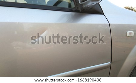 Accident, dents or bumps on the side of the front door of the driver's side waiting for repair, rust on car after accident, silver car with left front door and tyre.