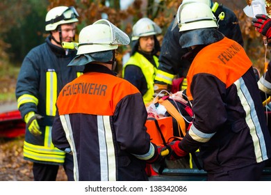 Accident - Fire Brigade And Rescue Team Pulling Cart With Wounded Person Wearing A Neck Brace And Respirator