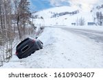 Accident on a winter snowy track with a black car skidding and falling into a ditch due to ice. Safety and poor driving on the road.