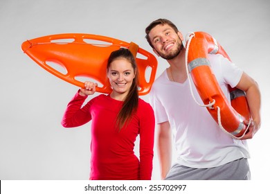 Accident Prevention And Water Rescue. Young Man And Woman Lifeguard Couple On Duty Holding Ring Buoy Float Lifesaver Equipment Having Fun On Gray