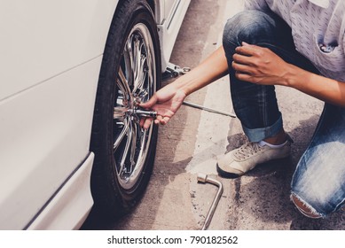 Accident With Punctured Tires. Traveler Man Changing Flat Tire On The Road. Replacing The Tires On The Car,  Attaching A Spare Wheel. 