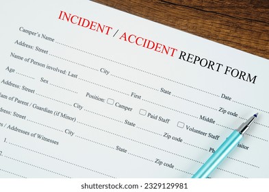 Accident report form with pen on wooden background.