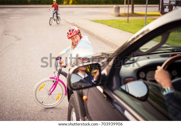 事故だ。自転車の上の小さな女の子が車の前の道を横切る