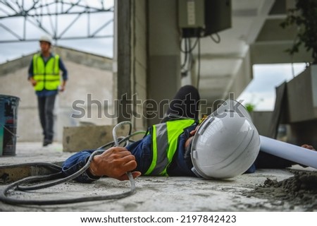 Accident from work of an electrical engineer or maintenance worker lying unconscious and tensed hands on floor near power control box after an accident short circuit while someone is coming to help