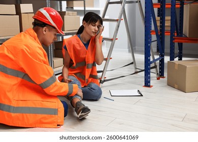 Accident at work. Man helping his injured colleague in warehouse