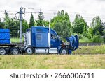 Accidentally broken down while driving  blue big rig semi truck with open hood and loaded flat bed semi trailer stands on the highway shoulder waiting for mobile repair service road assistant