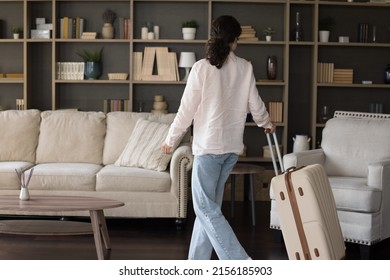 Accommodation, happy holidays, client of services vacation rentals around the world, start life at own or rented flat concept. Young female guest or new tenant enters living room with luggage suitcase