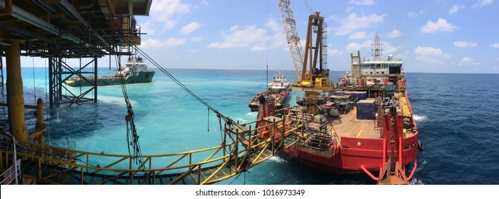 Accommodation work barge transfers personnel to crew boat during simultaneous operations with jack up rig at wellhead platform.